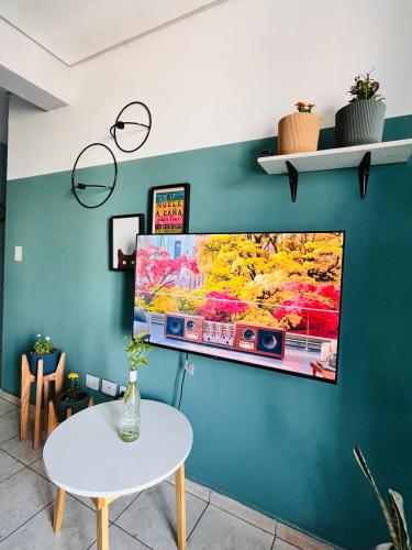 a tv hanging on a blue wall with a table at Altos de Barrio Sur in San Miguel de Tucumán