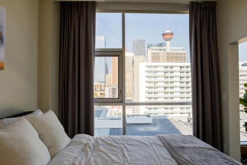a bedroom with a bed and a large window at City Views Walk to Calgary Tower and Stampede in Calgary