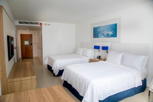 a hotel room with two beds with white sheets at Holiday Inn Acapulco La Isla by IHG in Acapulco