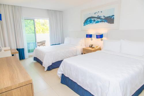 a hotel room with two beds and a window at Holiday Inn Acapulco La Isla by IHG in Acapulco