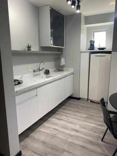 a kitchen with white cabinets and a sink and a refrigerator at Saint Sebastian Flat 613 - Com Hidro! Até 3 pessoas, Duplex, no Centro in Jaraguá do Sul