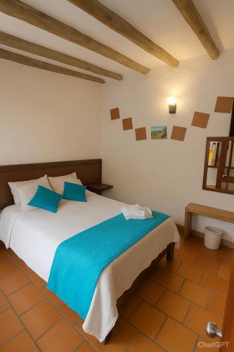 a bedroom with a large white bed with blue pillows at Hotel - Hospedería Villa Palva in Villa de Leyva