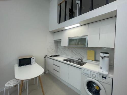 a white kitchen with a sink and a washing machine at 복층 오피스텔 in Tujŏng-dong