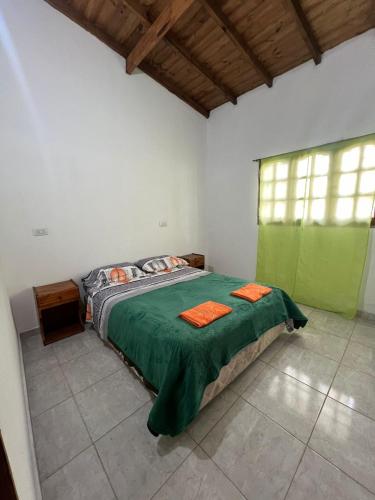 ein Schlafzimmer mit einem Bett mit grüner Bettwäsche und einem Fenster in der Unterkunft Cabañas del Sur in Mar del Plata