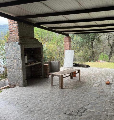 a stone fireplace with a bench and a table at Casa Portezuelo in San Javier