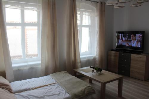 a bedroom with a bed and a tv and a table at Stara Kamienica Centrum in Mrągowo