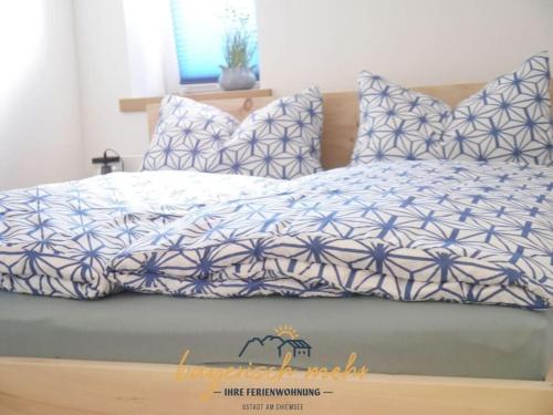 a bed with a blue and white comforter and pillows at Bavarian holiday apartment more in Gstadt am Chiemsee