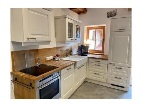 a kitchen with white cabinets and a sink at Chalet Hochgern in Staudach-Egerndach