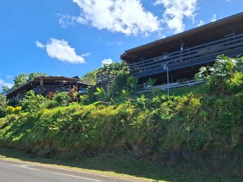 a building on a hill next to a road at Tehuarupe Surf Studio 2 in Haapiti