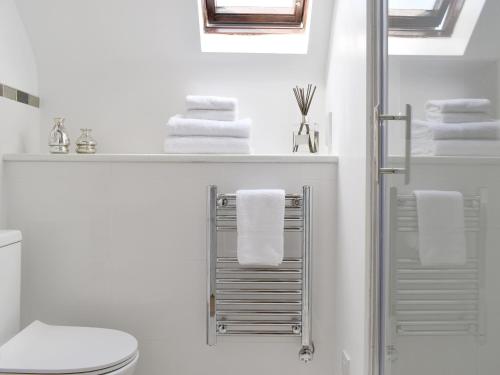 a white bathroom with a towel rack and a toilet at Brameley in Cheriton Bishop
