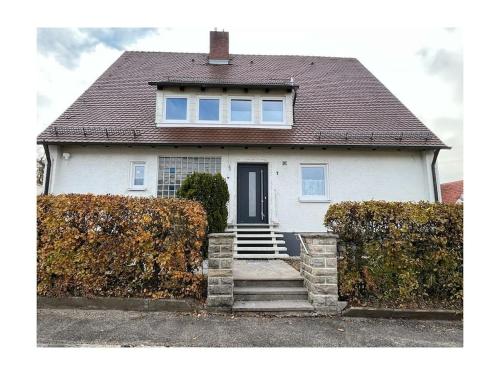 a white house with a black door and stairs at Holiday home with 2 bedrooms in Schopfloch