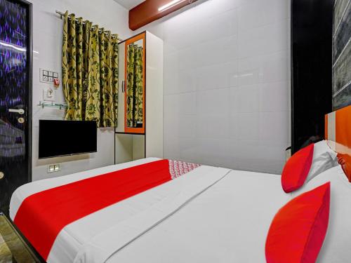 a bedroom with a red and white bed and a tv at OYO Flagship Hotel Gangeshwar in Anand