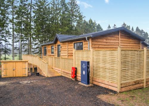 a large wooden cabin with a large deck at Thirlestane Woodland Lodges in Lauder