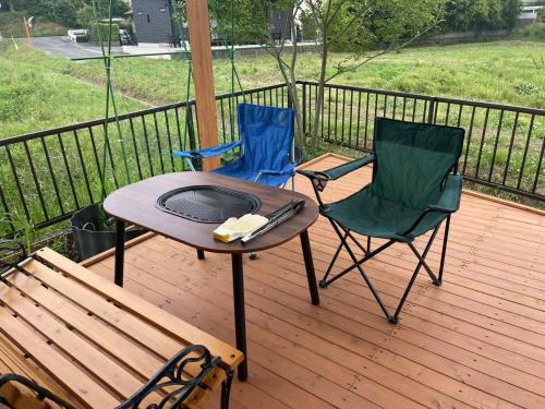 a patio with two chairs and a table and a grill at 田辺ハウス in Kafuri