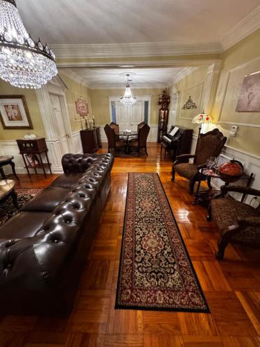 a living room with a leather couch and a rug at Opus House Historic Natchitoches in Natchitoches