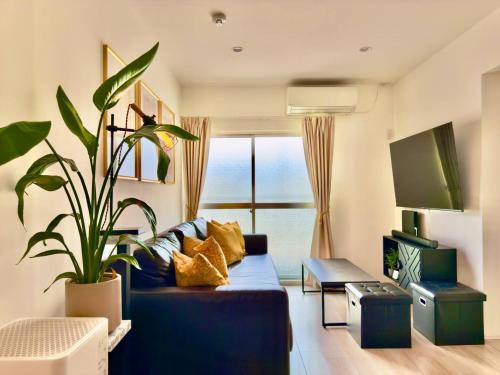 a living room with a blue couch and a plant at 4 min to Osaka Metro King bed 30 sec to 7-Eleven in Osaka