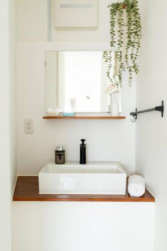 a white sink in a bathroom with a window at 4 min to Osaka Metro King bed 30 sec to 7-Eleven in Osaka