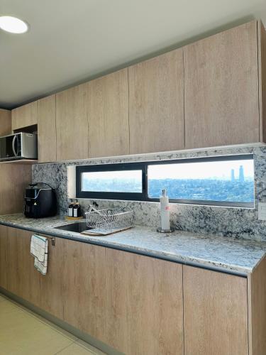 a kitchen with a counter top with a window at Modern 2BR Condo in Providencia, City Views, Pool & Gym in Guadalajara