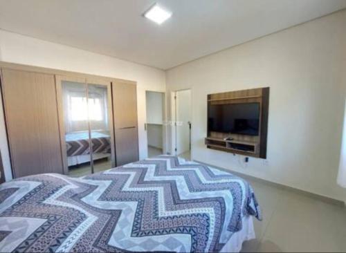 een slaapkamer met een bed en een flatscreen-tv bij Casa com 4 quartos com piscina próximo da praia do campeche in Florianópolis