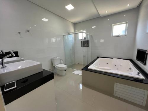 een badkamer met een bad, een wastafel en een toilet bij Casa com 4 quartos com piscina próximo da praia do campeche in Florianópolis