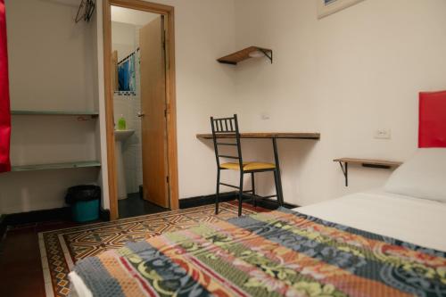 a bedroom with a bed and a desk and a chair at Havana Dance School & Hostel in Cali