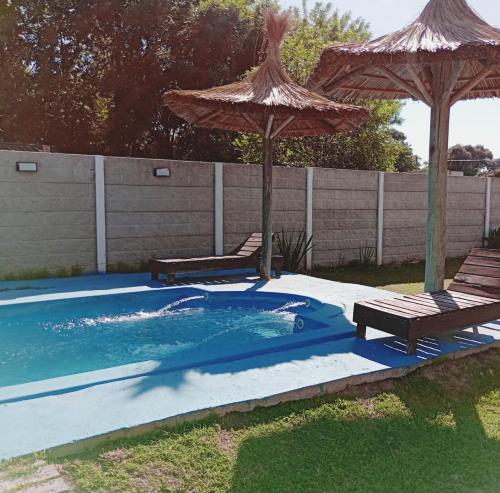 サン・ヴィセンテにあるQuinta Rufina San Vicenteのスイミングプール(パラソル2つ、ベンチ2台付)