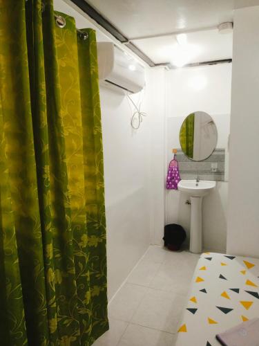 a bathroom with a green shower curtain and a sink at Ziah's Guest House in San Vicente