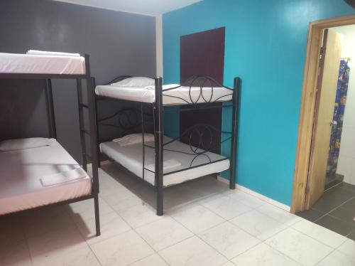 a room with three bunk beds and a blue wall at Havana Dance School & Hostel in Cali