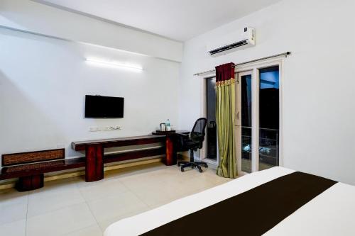 a bedroom with a bed and a desk and a television at Super Townhouse Medavakkam Near Jayachandran in Chennai