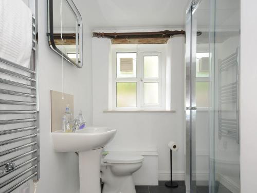 a bathroom with a sink and a toilet and a window at The Granary in Saint Minver