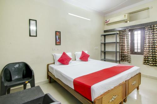 a bedroom with a bed with red pillows and a chair at Hotel O HAPPY RESIDENCY in Bībīnagar