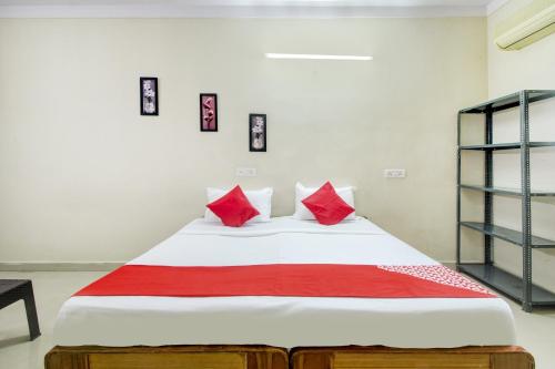 a bedroom with a bed with red pillows on it at Hotel O HAPPY RESIDENCY in Bībīnagar