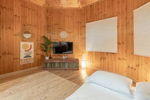 a bedroom with a bed and a tv and wooden walls at Gamsung Jeju Stay in Jeju