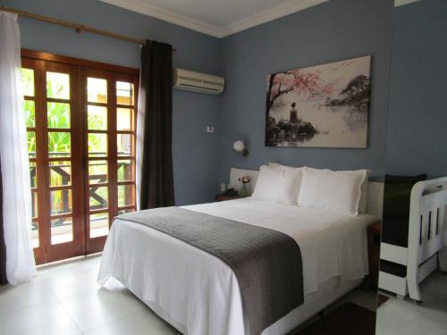 イリャベラにあるIlha flat Hotel Suíte Swaenen IIの白いベッドと窓のある寝室
