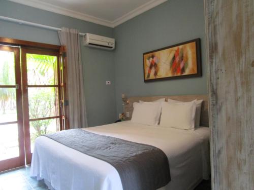 Un dormitorio con una cama blanca con una ventana. en Ilha flat hotel suíte Swaenen, en Ilhabela