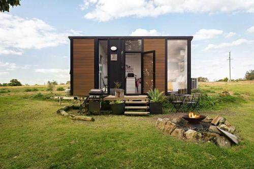 Una pequeña casa con fogata en un campo en Sunset Retreat by Tiny Away, en Nanango