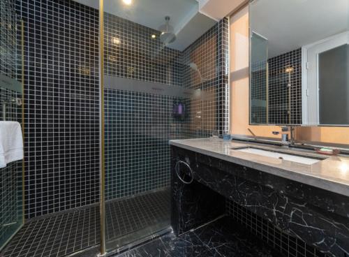 a bathroom with a shower and a sink and a mirror at Mercure Xiamen Exhibition Centre in Xiamen