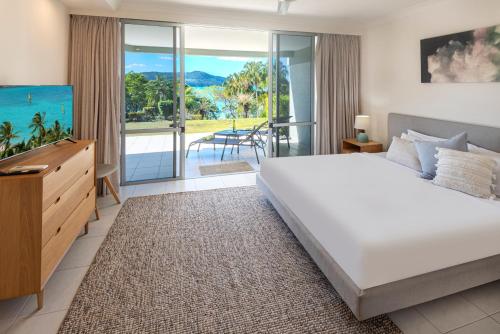 a bedroom with a large white bed and a balcony at Lagoon 004 by HamoRent on Hamilton Island in Hamilton Island