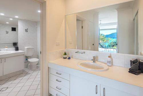 a bathroom with a sink and a toilet and a mirror at Lagoon 004 by HamoRent on Hamilton Island in Hamilton Island