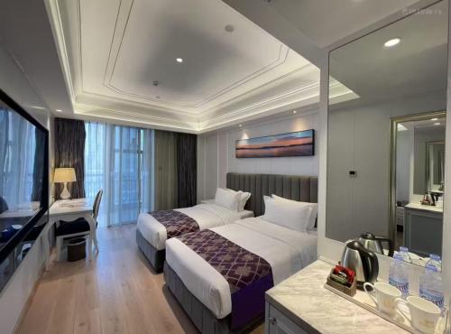 a hotel room with two beds and a television at Mercure Xiamen Exhibition Centre in Xiamen