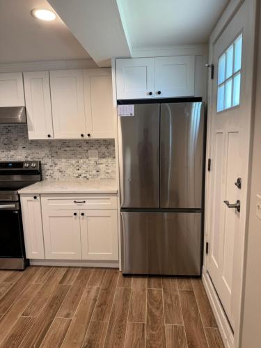 a kitchen with white cabinets and a stainless steel refrigerator at Calm Retreat in Plainview