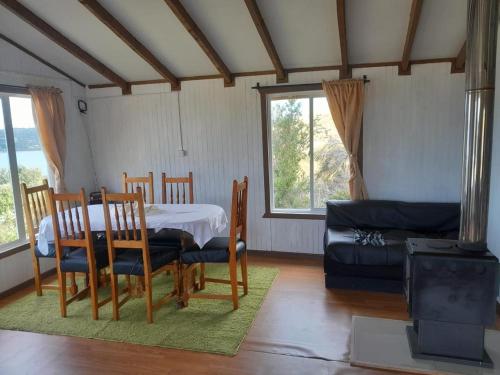 a dining room with a table and chairs and a couch at Cabaña Muñoz Navarro in Huildad