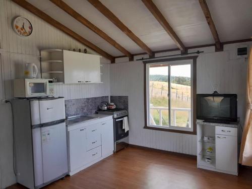 a kitchen with white appliances and a large window at Cabaña Muñoz Navarro in Huildad