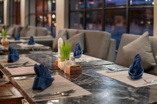 a table in a restaurant with blue napkins on it at Swarga Suites Bali Berawa, Marclan Collection in Canggu