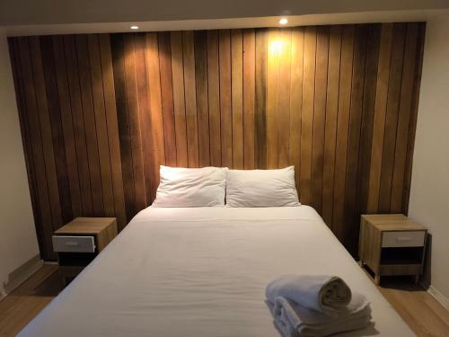 a bedroom with a large white bed with wooden walls at Sky Aloja Hotel - Mall Centro in Osorno
