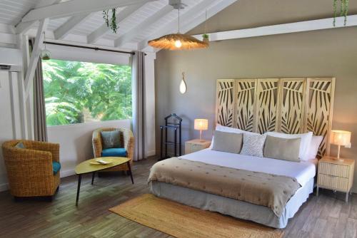 a bedroom with a bed and a chair and a window at Koho SXM - ex Hevea Hotel in Grand Case