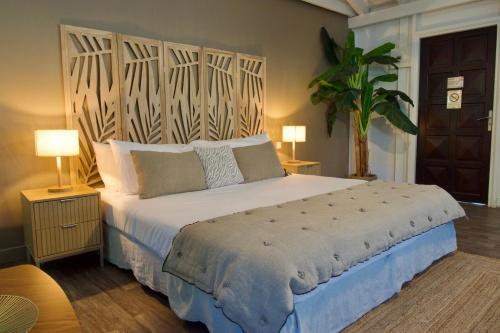 a bedroom with a large bed with a wooden headboard at Koho SXM - ex Hevea Hotel in Grand Case
