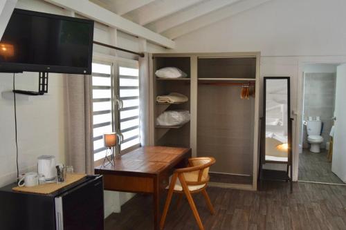 a room with a desk and a television and a bathroom at Koho SXM - ex Hevea Hotel in Grand Case