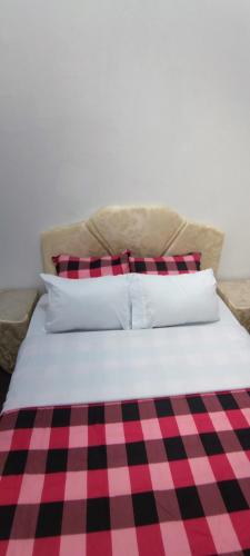 a bed with red and black checkered sheets and pillows at Cuba linda, alojamiento, hospedaje 1 habitación económico in Asuncion