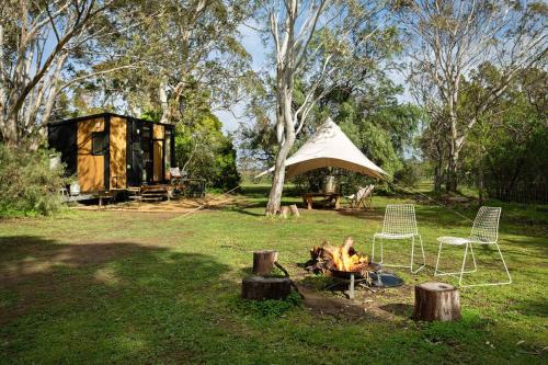 a tent and chairs and a fire in a field at Creekside at Peasant Farm by Tiny Away in Willunga
